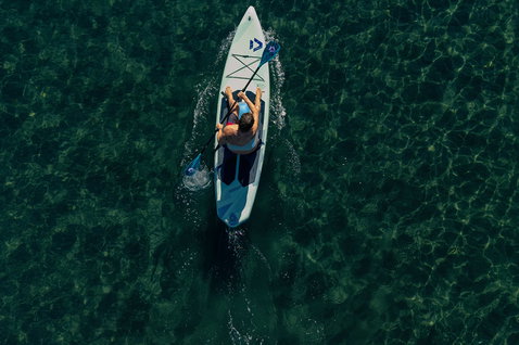 Duotone Blitz Air SLS inflatable SUP in kayak configuration being paddled on clear turquoise water