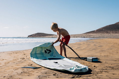 Duotone Now Air SLS kids iSUP being inflated on a sunny sandy beach with electric pump