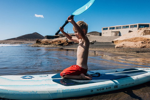 Duotone Now Air SLS Kids iSUP beim Stand Up Paddling an einem felsigen Strand