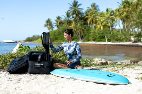 Borsa da viaggio Duotone Gearbag Foil Assist aperta su una spiaggia tropicale con tavola da foil