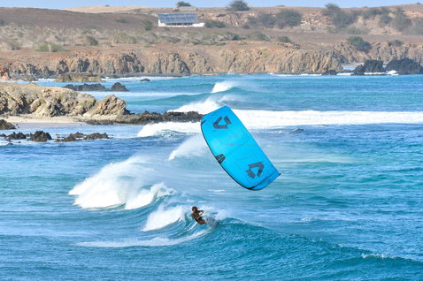 Duotone D/LAB LEI kite during wave riding at a rocky ocean coastline