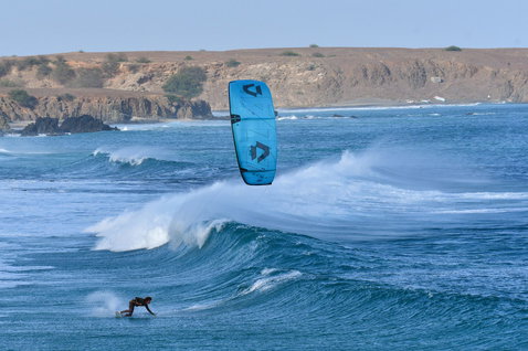 Duotone D/LAB LEI kite during wave riding at ocean coastline with rocky cliffs