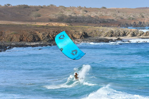 Duotone D/LAB LEI kite during wave riding at a rocky ocean coastline