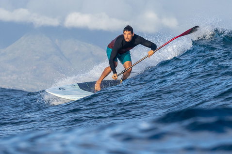 Duotone Cosmic SLS SUP board de vague pendant le surf SUP sur l'océan avec montagnes en arrière-plan