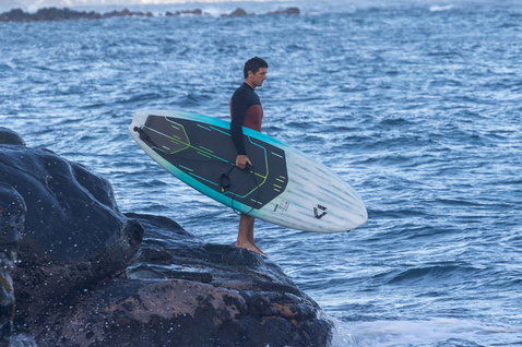 Duotone Cosmic SLS SUP hardboard vagues en session de surf sur une côte rocheuse en bleu marine et turquoise