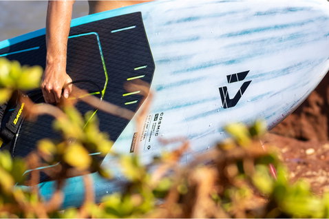 SUP de vague Duotone Cosmic SLS transporté sur un littoral rocheux