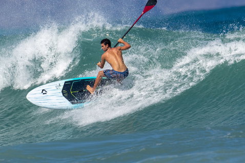 Duotone Cosmic SLS planche SUP de vagues lors du surf sur l'océan en bleu sarcelle et blanc