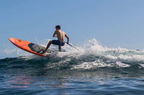 Duotone Cosmic hardboard SUP de vague lors du surf en SUP sur une vague océanique en orange