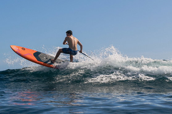 Duotone Cosmic SUP wave hardboard during SUP surfing on an ocean wave in orange