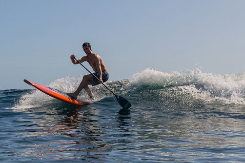 Duotone Cosmic SUP wave hardboard lors du SUP surf sur l'océan en orange