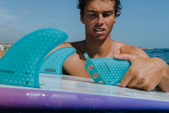 Duotone Cosmic SUP wave hardboard thruster fins in teal during wave surfing on the ocean
