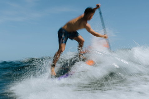 Duotone Cosmic SUP planche de vague lors du surf en mer en bleu et orange