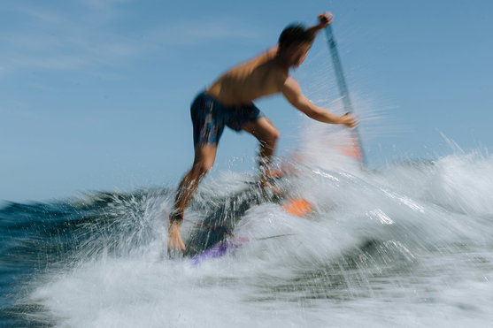 Duotone Cosmic SUP wave hardboard during wave surfing on the ocean in blue and orange