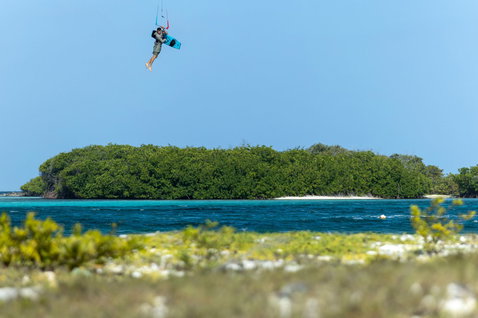 Duotone Big Air Handle lors d'un trick Big Air en kitesurf au-dessus d'eaux tropicales turquoise