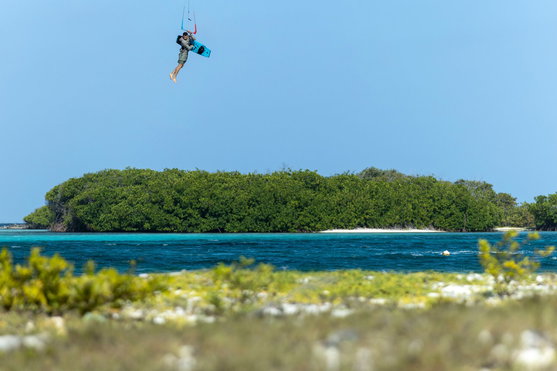 Duotone Big Air Handle lors d'un trick Big Air en kitesurf au-dessus d'eaux tropicales turquoise