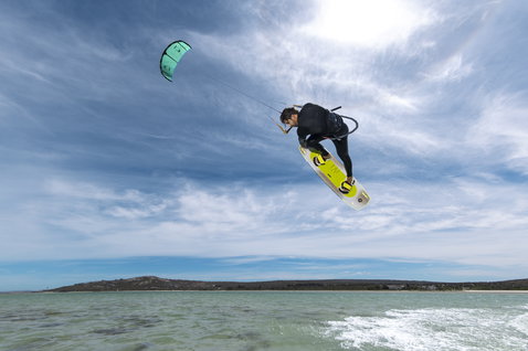 Duotone Evo LEI Kite beim Kitesurfen über dem Ozean mit Twintip-Kiteboard in mintgrün und weiß