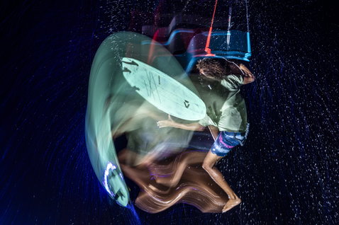 Duotone Neo Wave Bundle Whip SLS Surfboard beim Wellenreiten in der Nacht mit Lichtspuren und Regen