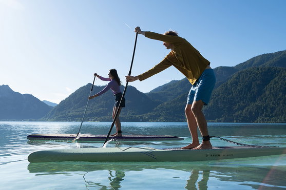 Duotone Raven touring SUP hardboard 12'6" in dark teal during stand-up paddling on a mountain lake