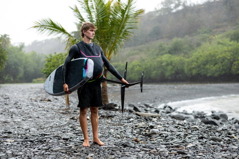 Duotone Paradox SLS planche de foil lors de wing foiling sur une plage rocheuse tropicale sous la pluie