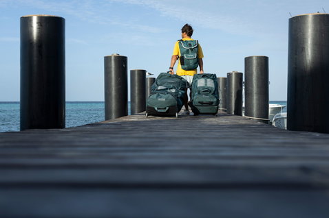 Duotone Combibag gear bag during travel to the ocean on a jetty in dark navy and teal