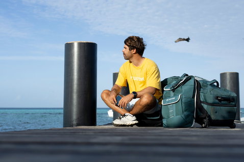 Duotone Combibag wheeled gear bag in teal on a dock by the ocean