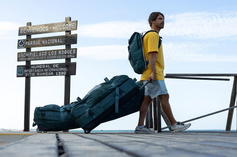 Duotone Team Bag wheeled travel gear bag during kiteboarding trip on pier at Los Roques in dark teal