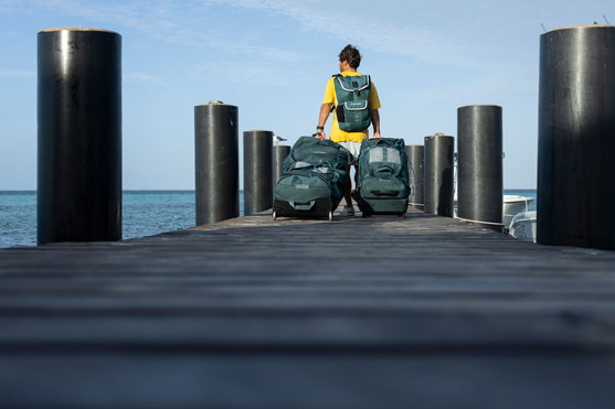 Mala de viagem Duotone Travelbag em uso num cais junto ao oceano