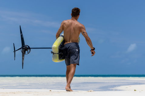 Duotone Midfish Air tavola eFoil gonfiabile con foil portata su una spiaggia tropicale