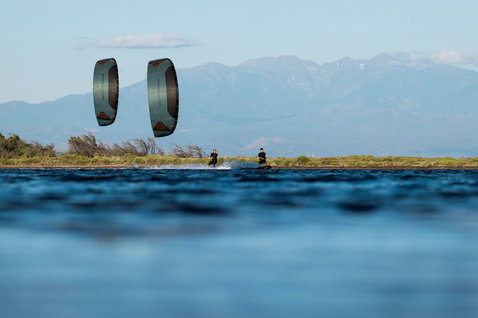 Duotone Evo SLS Porsche Edition LEI kite during kitesurfing on flat water with mountain backdrop