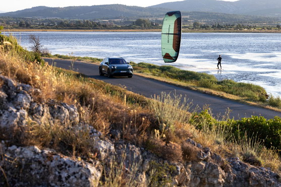 Duotone Evo SLS LEI Kite beim Kitesurfen an einer Küstenlagune mit Porsche im Hintergrund