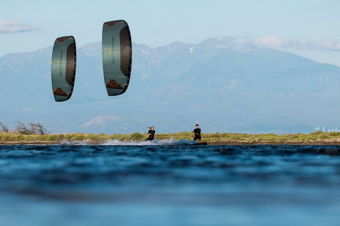 Duotone Evo SLS Porsche Turbo LEI kite during kitesurfing on a mountain lagoon in teal and copper