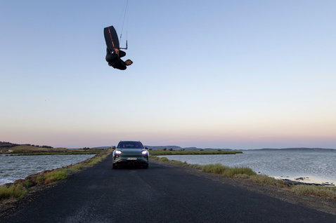 Duotone Jaime SLS Porsche Turbo Edition twin-tip kiteboard during Big Air kiteboarding above a Porsche Cayenne at the coast