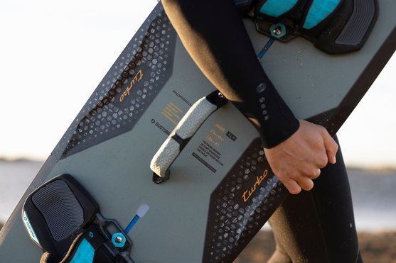 Duotone Jaime SLS Porsche Turbo Edition twin-tip kiteboard 136 cm en gris ardoise pendant le kitesurf sur la plage