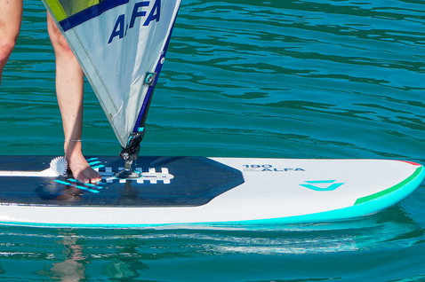 Planche de windsurf Duotone Alfa HD 180 L en blanc et turquoise lors d'une session de windsurf sur eau calme