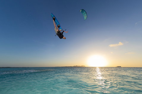 Duotone Evo D/LAB LEI kite during kitesurfing with inverted aerial trick over a turquoise lagoon at golden hour