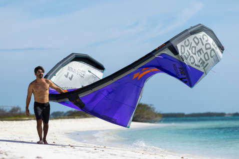Duotone Dice SLS LEI kite during kitesurfing at a tropical white sand beach in violet blue