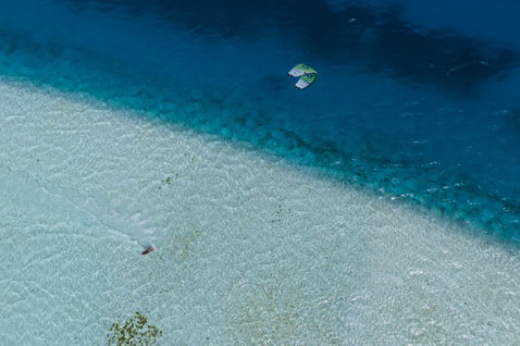 Duotone Neo SLS LEI Kite beim Wave Kitesurfen über türkisfarbenem Riff aus der Vogelperspektive