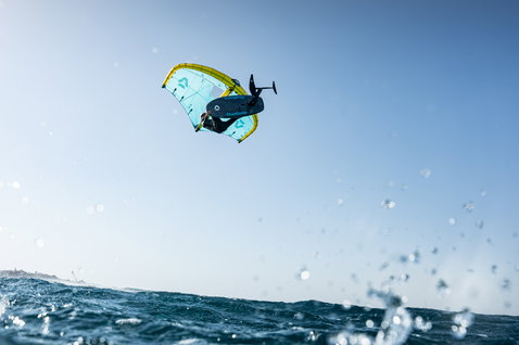 Duotone Unit D/LAB foil wing durante un aerial di wing foiling sull'oceano in blu acciaio e chartreuse