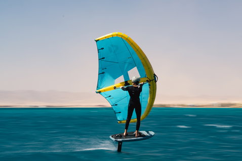 Duotone Unit D/LAB foil wing in ciano e giallo durante il wing foiling sull'oceano turchese