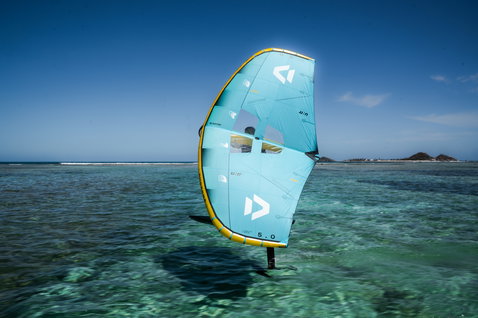 Duotone Unit D/LAB foil wing 5,0 m in blu acqua e oro durante wing foiling in una laguna tropicale