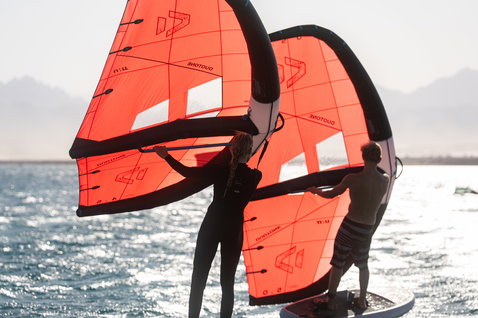 Duotone Unit Foilwing beim Wing Foiling an einer sonnigen Küste in koralle rot