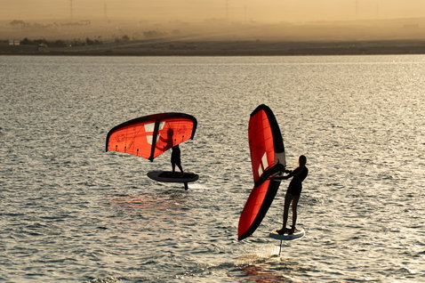 Duotone Unit Foilwing beim Wing Foiling auf ruhigem Wasser im goldenen Abendlicht mit zwei Fahrern