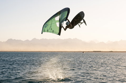 Duotone Sky Style SLS Foilboard beim Wing Foilen in der Luft über dem Wasser bei goldenem Licht