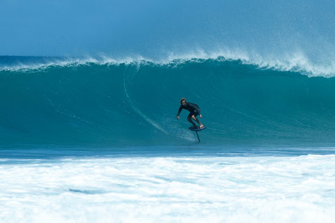 Duotone Crush SLS prone foil board during foiling in front of a large wave in Guadeloupe