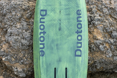 Planche de foil Duotone Trace SLS en vert sauge, vue pont avec construction carbone SLS sur rochers