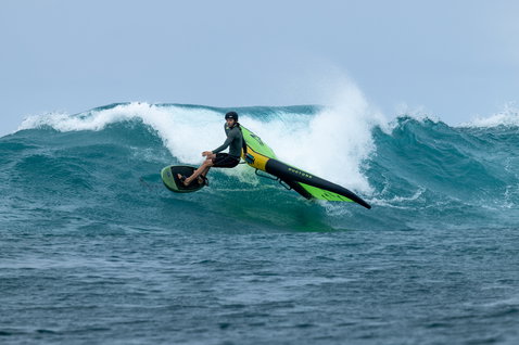 Duotone Unit SLS foil wing during wing foiling on an ocean wave in lime green and yellow