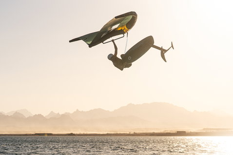 Duotone Front Wing Pop D/LAB beim Wing Foiling mit Aerial-Freestyle-Trick über dem Meer im Gegenlicht