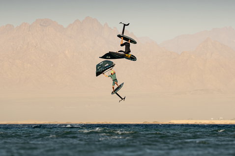 Duotone Unit SLS Frontwing beim Wing Foiling mit zwei Athleten in der Luft über dem Meer vor Wüstengebirge