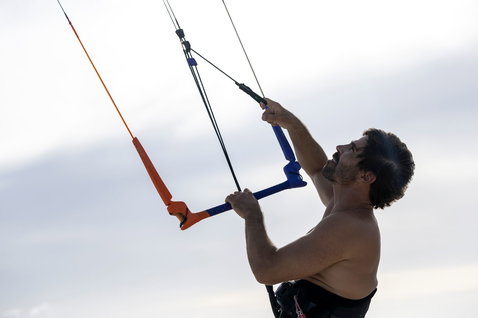 Duotone Trust Bar quad control bar during kitesurfing held overhead in orange and blue