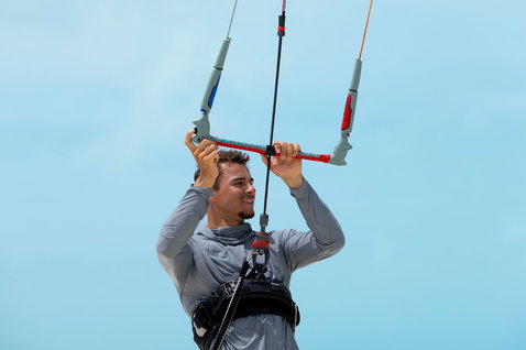 Duotone Click Bar Quad Control kite control bar during kitesurfing, rider holding bar overhead against blue sky